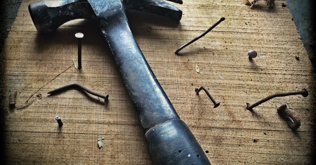 A weathered hammer surrounded by bent nails on a wooden plank, capturing the essence of carpentry work.